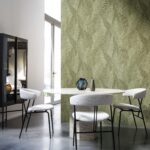 Moderne eetkamer met vier witte stoelen, een ronde tafel van natuursteen en een groene wand met het Tangram Bounty 24020 behang met bladpatroon.