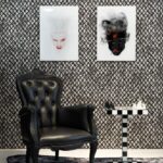 Zwartleren fauteuil naast schaaktafel met zwart-wit blokpatroon, voor een muur met artistieke portretten en grafisch behang.