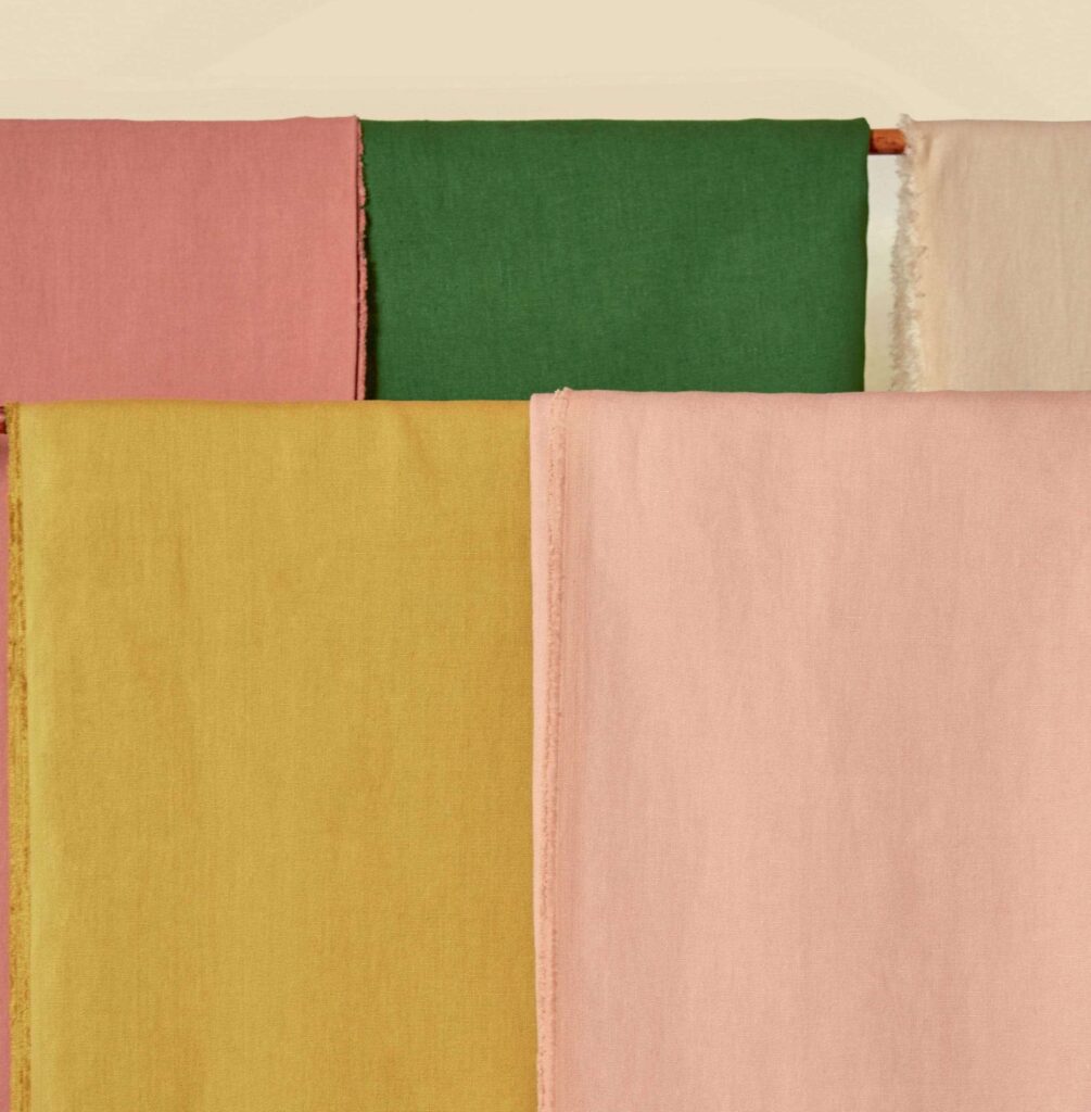 Stoffen uit de Elitis Kaila LI 890 25 collectie in roze, groen, okergeel en beige opgehangen naast elkaar.