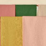 Stoffen uit de Elitis Kaila LI 890 25 collectie in roze, groen, okergeel en beige opgehangen naast elkaar.