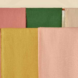 Stoffen uit de Elitis Kaila LI 890 25 collectie in roze, groen, okergeel en beige opgehangen naast elkaar.