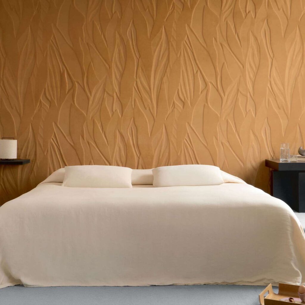 Slaapkamer met goudkleurig 3 D textielbehang met bladeren op een zachte velours ondergrond