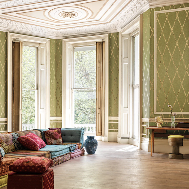 woonkamer met het Fornasetti-behang Cammei een wieberpatroon en klassieke munten groen goud