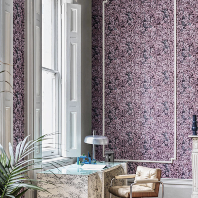 Woonkamer met het Fornasetti-behang Foglie e Scimmie met groene bladeren en tekeningen van aapjes tussen het gebladerte.