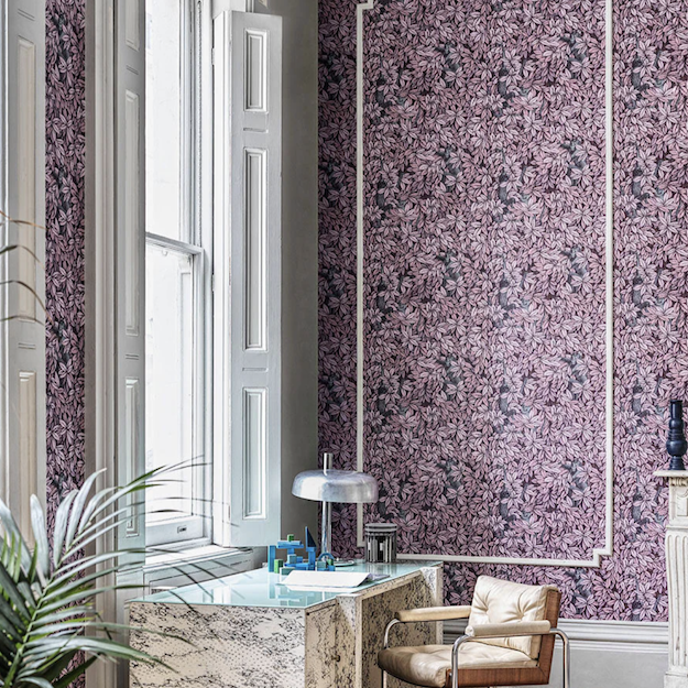 Woonkamer met het Fornasetti-behang Foglie e Scimmie met groene bladeren en tekeningen van aapjes tussen het gebladerte.