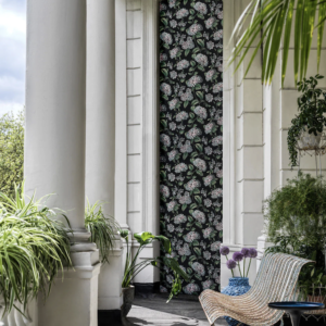 wwonkamer met het Fornasetti-behang Ramo di Ortensia met meerkleurige hortensia bloemen op een zwarte achtergrond