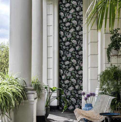 wwonkamer met het Fornasetti-behang Ramo di Ortensia met meerkleurige hortensia bloemen op een zwarte achtergrond
