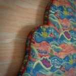 Detail van een geschulpt hoofdbord bekleed met de Andrew Martin stof meadow multi