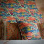 Detail van een geschulpt hoofdbord en kussen van de Andrew Martin stof meadow multi